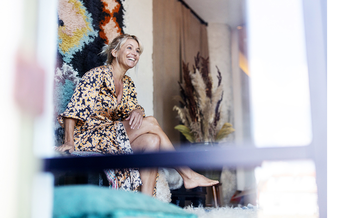 A happy woman, the chef, Tina Nordström, sits in a colorful environment