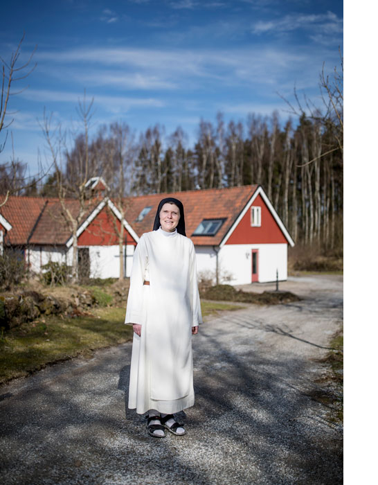 A nun is standing outside by an older house