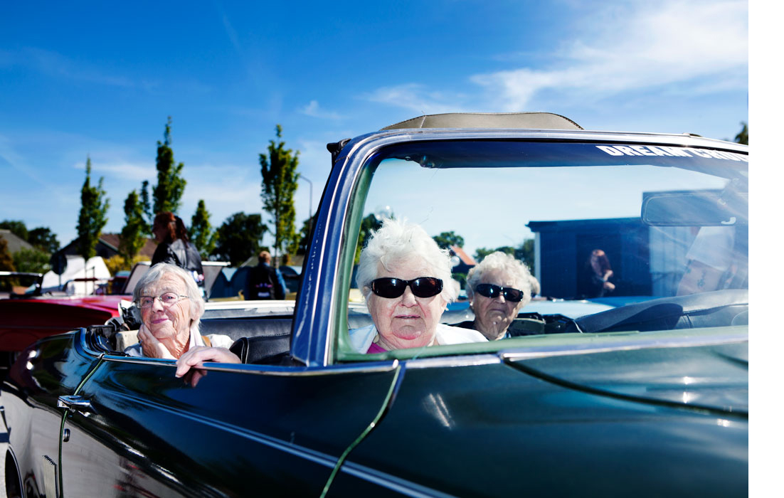 Three older women are sitting in a convertible