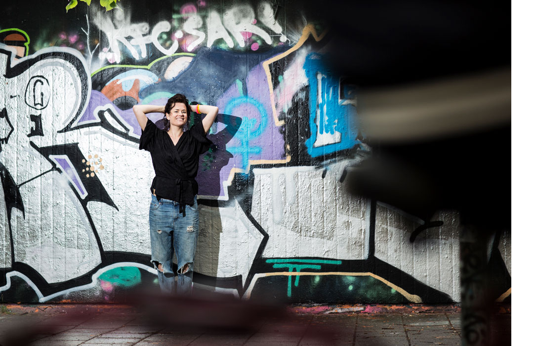 A woman is posing by a graffiti wall