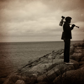 The photographer André stands with his camera slung over his shoulder by the sea