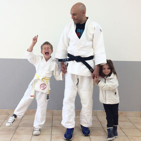 Photographer André stands with his children dressed in martial arts uniforms