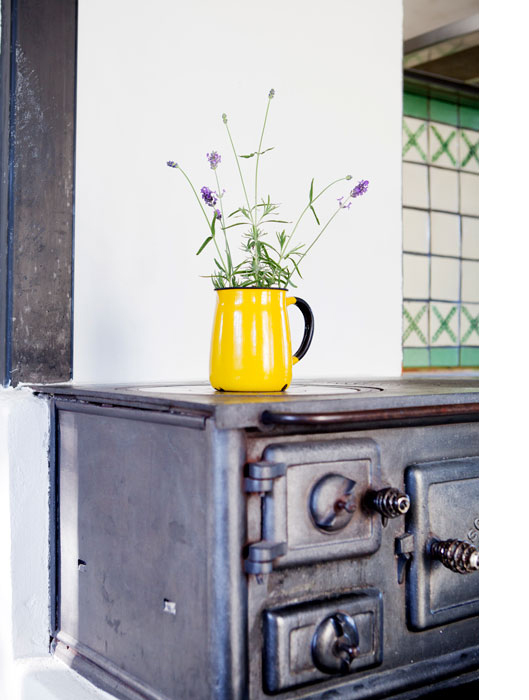 A yellow pot with lavender sits on an old stone fireplace