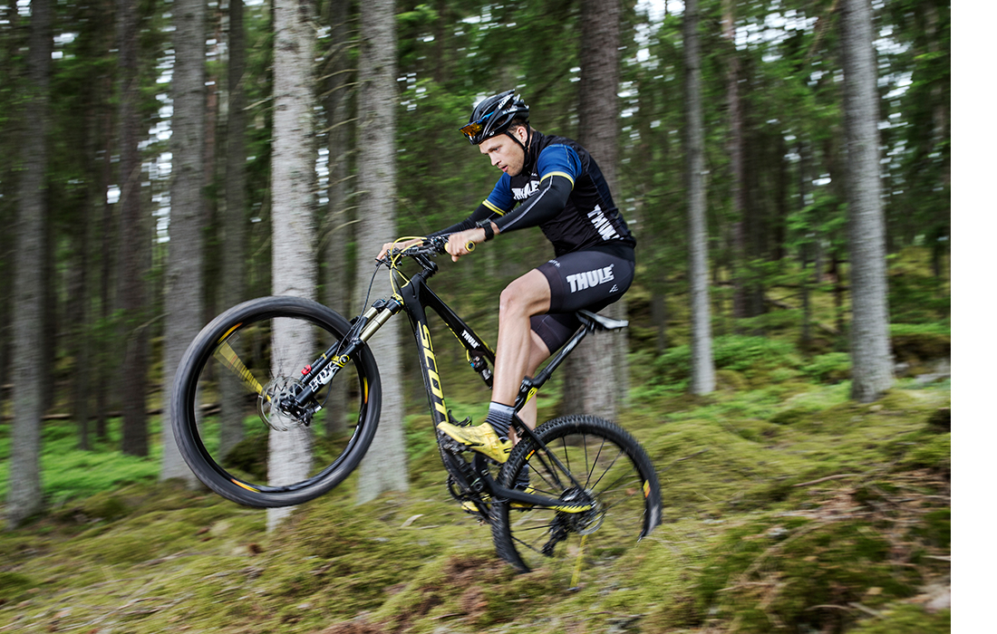 En ung man cyklar äventyrligt i skogen