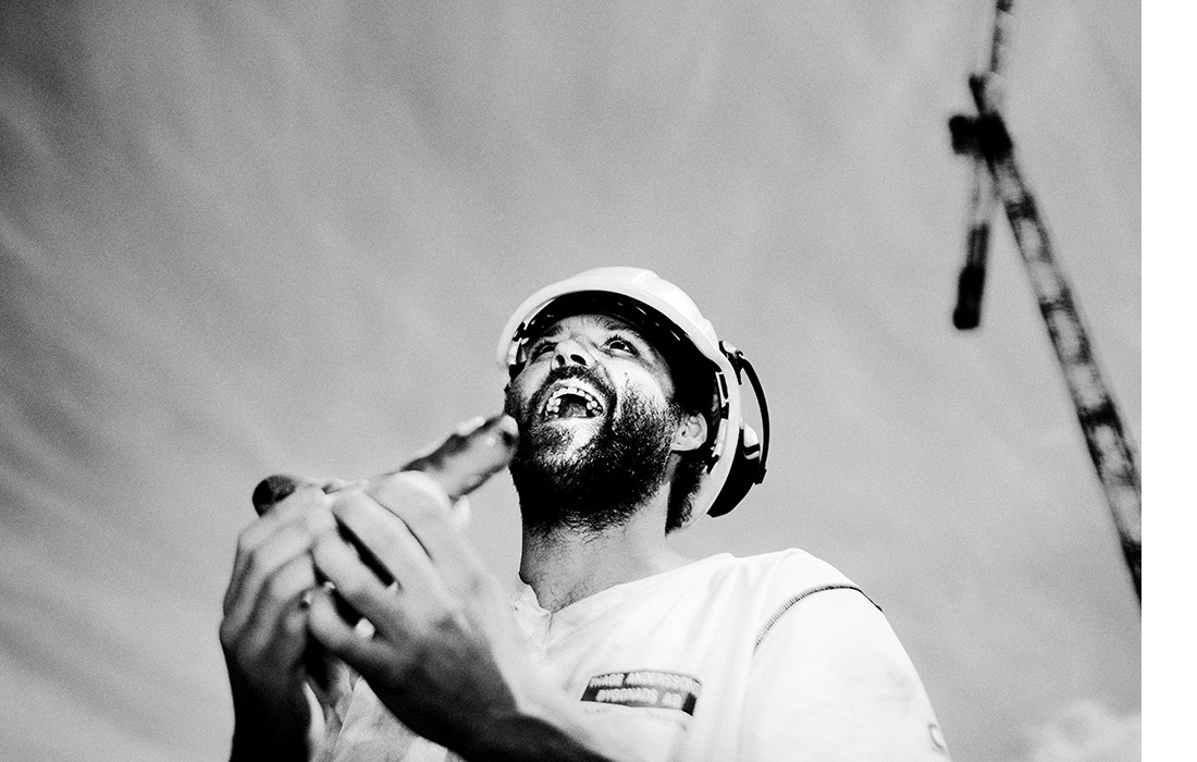 A happy worker is eating a hot dog at a construction site