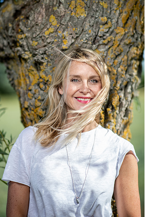 A happy woman poses in front of a tree