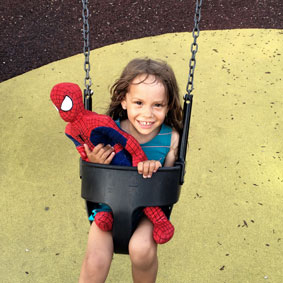 A girl is swinging with a Spider-Man stuffed toy